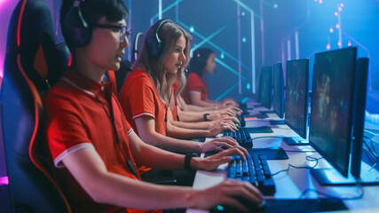 Diverse Esport Team of Pro Gamers Play in Mock-up RPG Strategy Video Game on a Championship. Stylish Neon Cyber Games Arena. Online Broadcasting of Tournament Event. Side View Shot © Gorodenkoff