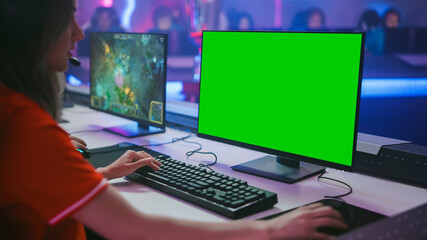 Pro Girl Plays Computer Game with Green Screen Display on a Championship. Diverse Esport Team of Pro Gamers Play in Mock-up Video Game. Stylish Neon Cyber Games Arena. Over The Shoulder Shot © Gorodenkoff
