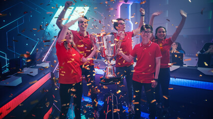Diverse Esport Team Winner of the Video Games Tournament Celebrates Victory Cheering and Holding Trophy in Big Championship Arena. Cyber Gaming Event with Gamers and Fans. © Gorodenkoff