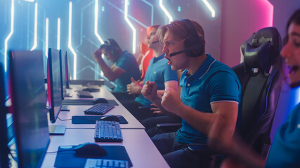 Diverse Esport Team of Pro Gamers Play in Computer Video Game and Win Championship, Celebrate with YES Gestures. Stylish Design Cyber Games Arena. Online Streaming of Tournament. Side View © Gorodenkoff