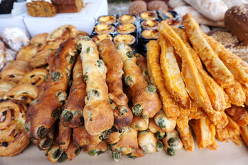 Pile of cheese olive stick and stick of bread with cheese, egg tart selling in farmer market