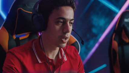 Professional Gamer Plays Computer Video Game Talking into Headset with Teammates on Championship. Diverse Esport Team of Pro Gamers Play in Computer Game. Stylish Neon Cyber Games Arena. Portrait Shot