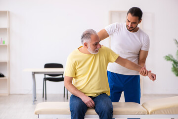 Obraz premium Old male patient visiting young male doctor chiropractor