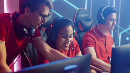 Diverse Esport Team of Pro Gamers Play in Video Game on a Championship, Talking Using Headsets, Trainer Explains Strategy. Stylish Neon Cyber Games Arena. International Tournament Event © Gorodenkoff
