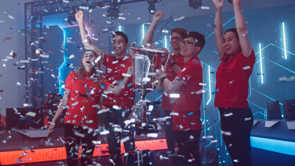 Diverse Esport Team Winner of the Video Games Tournament Celebrates Victory Cheering and Lifting Trophy in Big Championship Arena. Cyber Gaming Event with Gamers and Fans. © Gorodenkoff