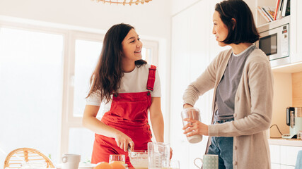 Happy Lesbian Couple Cooking Together in the Kitchen. Lovely Two Girls in Love Spending Time Together. Young Girlfriends Preparing Delicious Meal, Talking, Having Fun.