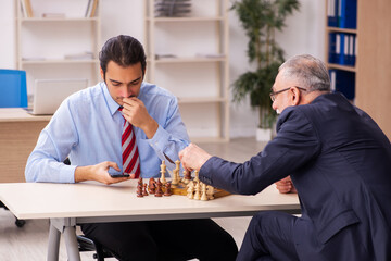 Two businessmen playing chess in the office