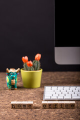 Close up view of a black work desk interior with a laptop computer, a cup of coffee,  paper, pen and, cactus with flowers black background