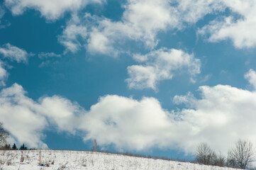 Above the snow-capped mountain top is a blue sky with white clouds.