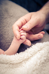 A small baby holds the Mother's hand and finger in search of protection..