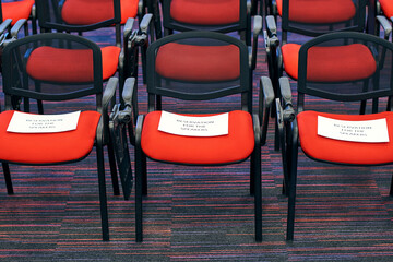 Red and black conference chairs in the auditorium with reservation for the speakers sign on them
