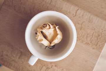 Small cup for tea with a saucer on a wooden background. A cup for coffee with a flower bud inside.