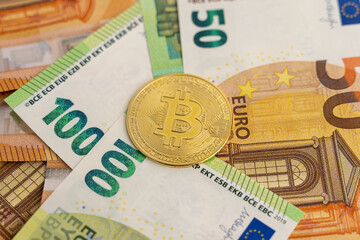 Bitcoin lying on euro banknotes. Crypto currency as payment or in exchange for paper money.