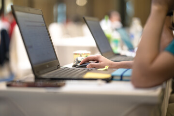 Action of a business person is typing on keyboard to make a report, with blurred background of bokeh lighting in business conference meeting. Close-up and selective at person hand.