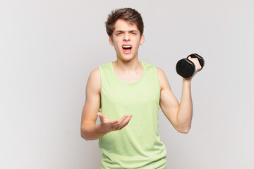 young boy looking angry, annoyed and frustrated screaming wtf or what’s wrong with you. dumbbell...