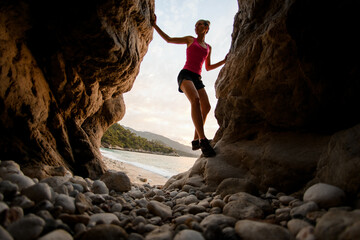 beautiful woman stands on stones in gorge against the background of beach