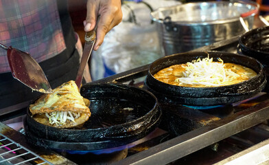 Fried mussel pancakes with egg in iron frying pan.Fried Mussels Thai Food.                 