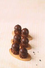 Shortcrust Oval Cookies with Chocolate Cream and Praline Bonbons on Top, on a light beige...