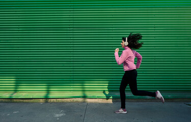 Fototapeta na wymiar Young woman listening to music while running