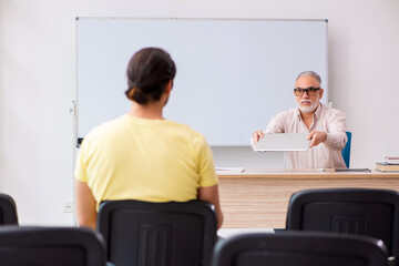 Fototapeta premium Young male student and experienced teacher in pandemic concept