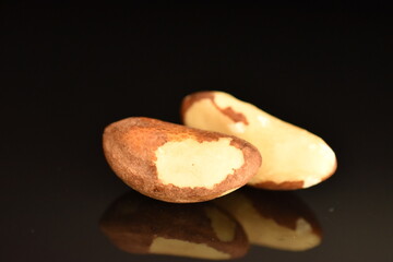 Two ripe organic Brazil nuts, close-up, isolated on black.