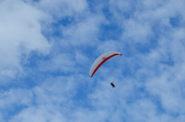 Fototapeta na wymiar Flying on a paraglider. Paraglider with two passengers on a background of blue sky