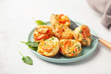 Egg muffins ( bites) and spinach leaves  in a plate on a gray background