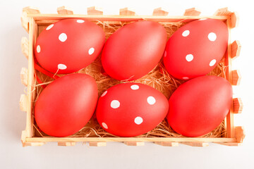 Decorative red Easter eggs in a small wooden box isolated on a white table .