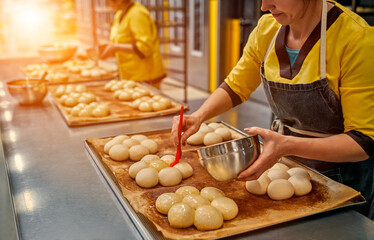 The bakers greases the buns with sunflower oil for further baking. Automated production of bakery products. Bread factory.