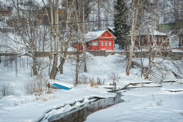 Red residential building on the banks of the frozen Shokhonka River in Plyos