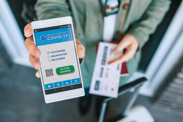 Unrecognizable woman showing covid passport on the smartphone at an airport control