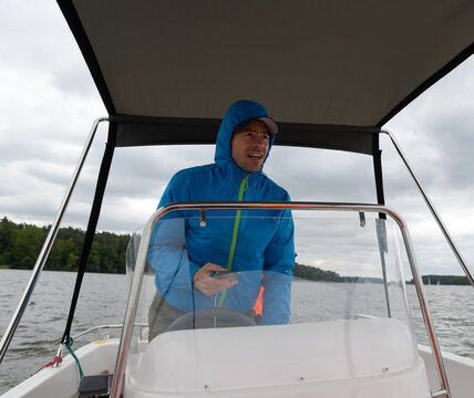 Steuermann oder Kapit&auml;n in einem blauen Windbreaker navigiert das Boot an einem windigen Tag.