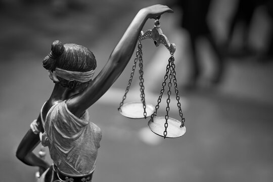 Rear view of themis statue with balance scales in black and white as a symbol of justice