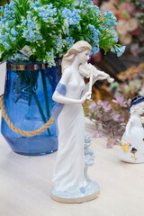 Obraz premium German porcelain figurine of a violinist girl. Ceramic figurine of the violoncellist in retro style with blue flowers on the table