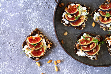 Canape, crostini or bruschetta with figs, bread, cheese on metal tray top view