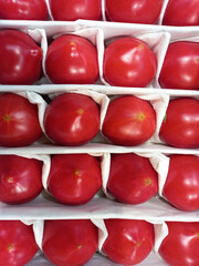 ripe red tomatoes in a box, packaging of vegetables for sale in the market or in a store.