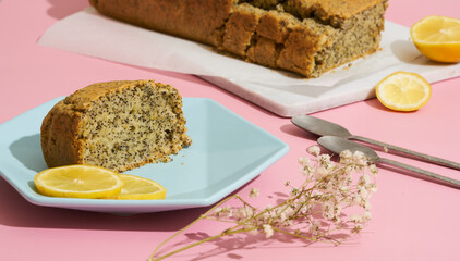 lemon poppy cupcake on a blue minimalistic plate on a pink background. Composition with hard shadows from the sun