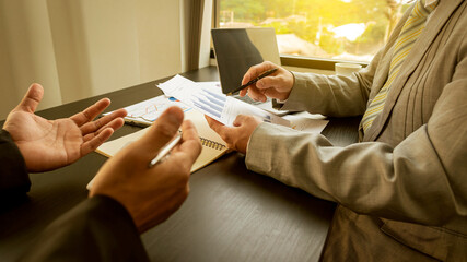 Fototapeta premium Two businessmen talked about graphs and analysis on finance companies and the use of calculator offices with papers and laptops and coffee mugs on the table.