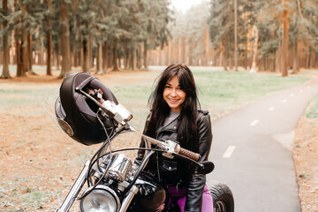 Naklejka na ściany i meble beautiful brunette riding a motorcycle in the park