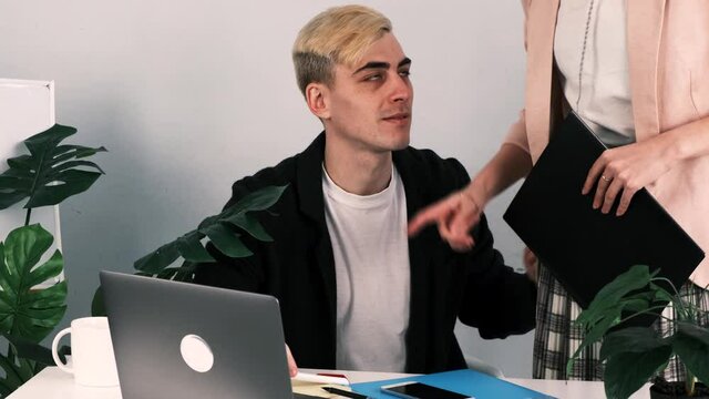 Harassment at work. Woman boss comes up to man and expresses her dissatisfaction with his work. Man grabs woman and puts her on his laps. Woman hits him on head with folder and leaves. Real time, 4k