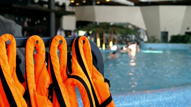 Orange life jackets. Life jackets are neatly hung out in front of the open water pool and are ready to use. Safety on the water.