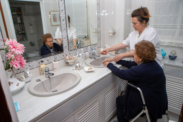 elderly caregiver helping to clean hands.
