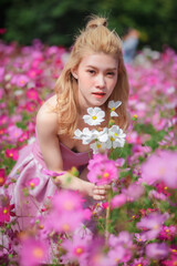 Beautiful girl in a field of cosmos flowers  on a sunny day