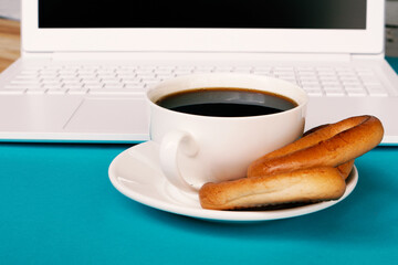A cup of coffee with dryers on a white notebook background on a blue background. Coffee break.