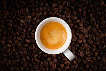 Cup of fragrant coffee on coffee beans background. View top
