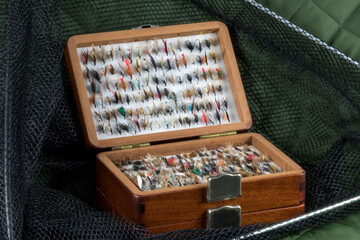 Wooden Fly Box with Trout Flies and Landing Net on an Outdoor Coat