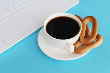A cup of coffee with dryers on a white notebook background on a blue background. Coffee break.