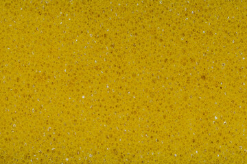 Yellow plastic scrubber with holes as a background. Cleaning sponge texture with visible porous close-up