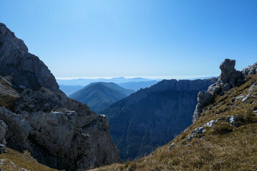 A panoramic view on Hochschwab mountain chains from the pathway leading to Hohe Weichsel. Sharp mountain slopes. Endless mountain chains, some shrouded with haze. Clear view. Blue sky above.