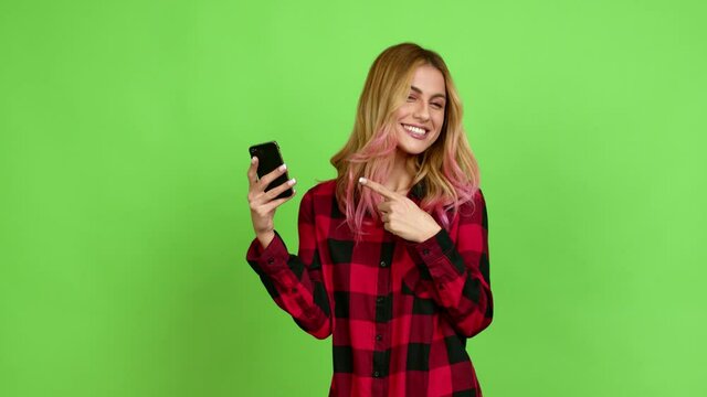 Young blonde woman using mobile phone over isolated background on green screen chroma key